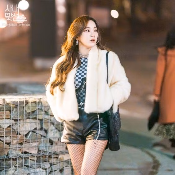 Set đồ gồm áo khoác lông phối cùng áo hoạ tiết kẻ caro, quần short da mặc cùng tất lưới "cosplay" một cô gái nổi loạn của Shin Ha Ri gây sốt các diễn đàn mạng.