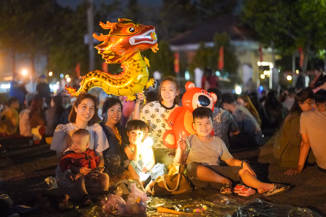 Chị Nguyễn Hoài Nhi, ngụ xã Bà Điểm, huyện Hóc Môn (TPHCM) ra đây từ 21h nên khá may mắn mới tìm được chỗ ngồi. Năm nay, cả gia đình chị Nhi có 7 thành viên ra đón giao thừa. "Ra hơi trễ mà tìm được chỗ ngồi vậy là quý rồi. Mấy năm trước bắn pháo hoa ở trung tâm không đi xem được vì vướng con nhỏ, nay gần nhà nên thuận tiện hơn", chị Nhi (ngoài cùng bên trái) chia sẻ. Chị Nguyễn Hoài Nhi, ngụ xã Bà Điểm, huyện Hóc Môn (TPHCM) ra đây từ 21h nên khá may mắn mới tìm được chỗ ngồi. Năm nay, cả gia đình chị Nhi có 7 thành viên ra đón giao thừa. "Ra hơi trễ mà tìm được chỗ ngồi vậy là quý rồi. Mấy năm trước bắn pháo hoa ở trung tâm không đi xem được vì vướng con nhỏ, nay gần nhà nên thuận tiện hơn", chị Nhi (ngoài cùng bên trái) chia sẻ.