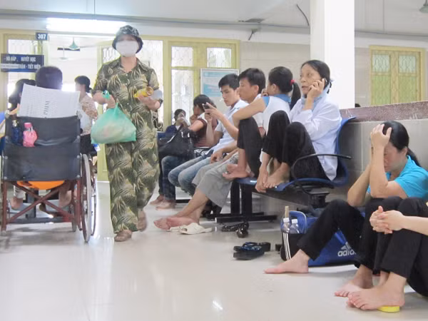 Bệnh nhân ngồi chờ khám trước phòng khám chuyên khoa 307, BV Bạch Mai vào sáng 25-7. Ảnh: Nguyễn Hoài. Bệnh nhân ngồi chờ khám trước phòng khám chuyên khoa 307, BV Bạch Mai vào sáng 25-7. Ảnh: Nguyễn Hoài
