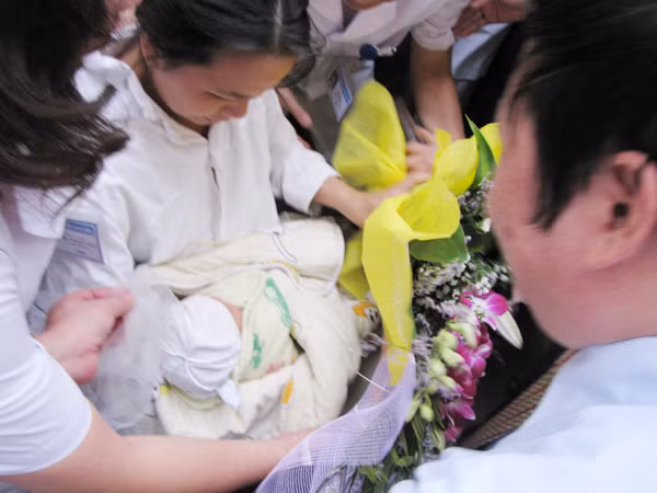 Khoảnh khắc chị Thơm nhận lại con từ đại diện bệnh viện và cơ quan điều tra. Ảnh: Lãng Phong