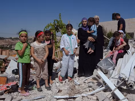 Một gia đình Palestine đứng trên nền ngôi nhà của họ ở khu dân cư Beit Hanina bị chính quyền Israel đập nát tháng 7/2009. Ảnh: Truth News