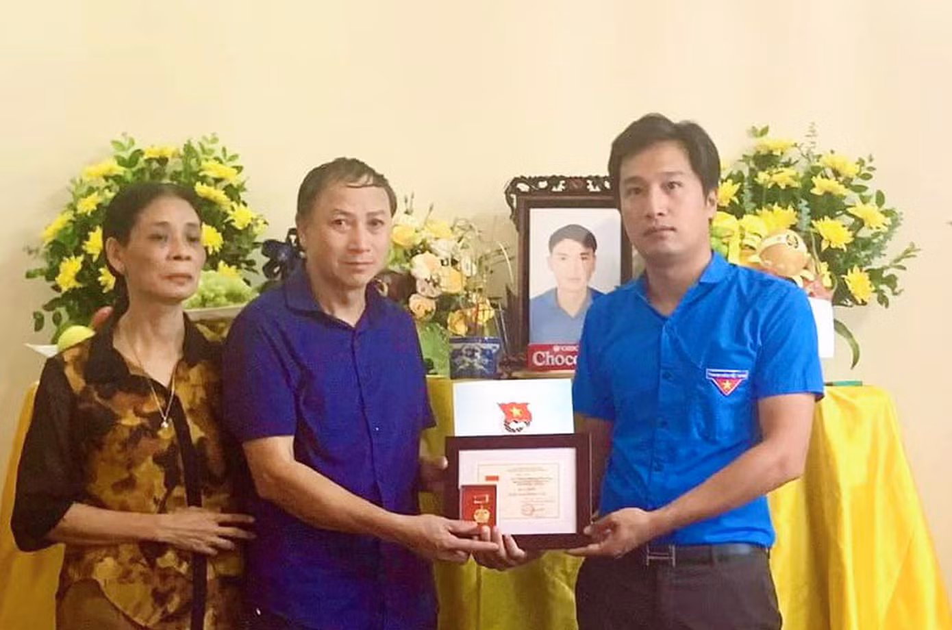 Anh Bùi Đức Giang trao quyết định truy tặng huy hiệu "Tuổi trẻ dũng cảm" đối với anh Phạm Hoàng Chương. Ảnh: TĐPT