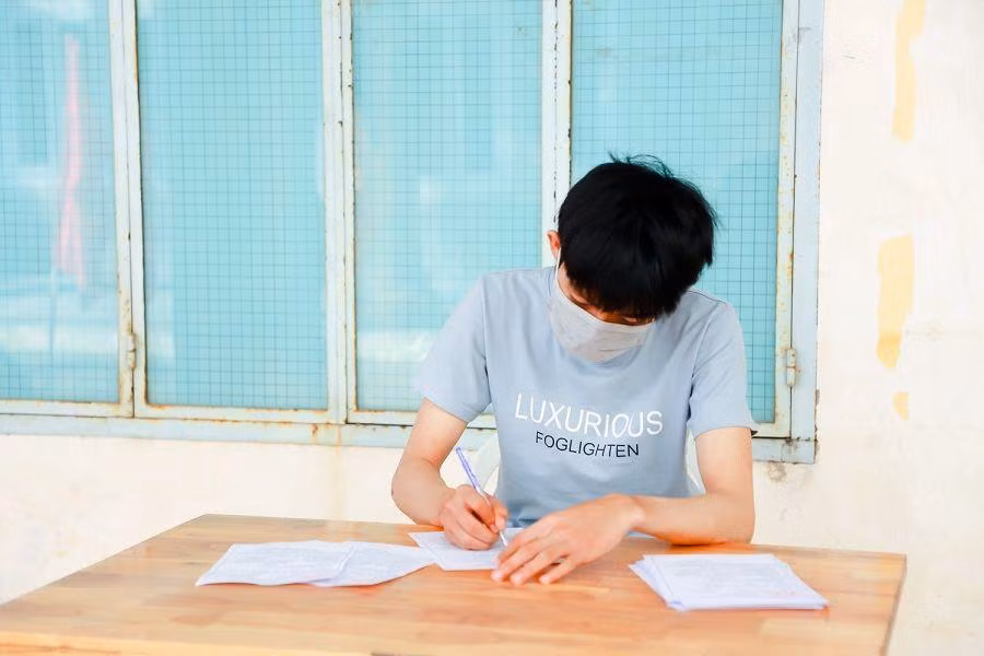 Các cử tri điền tờ khai y tế trước khi tiến vào khu vực bỏ phiếu. Ảnh: Văn Hoàng