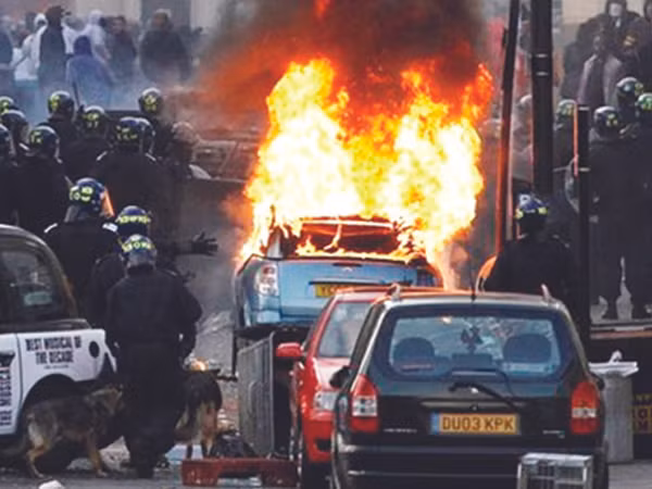 Cảnh sát chống bạo động đối phó tình trạng đốt xe ở London. Ảnh: BBC