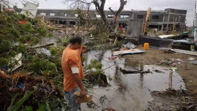 Dưới chân người đàn ông này là thi thể của một người dân khu vực. Những người Philippines dường như không thể khóc nổi bởi đã có quá nhiều người thiệt mạng do bão Haiyan