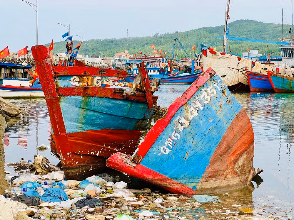 Chị Đoàn Thị Chung (trú phường Phổ Thạnh, thị xã Đức Phổ) cho hay, ngoài xác tàu và rác thải, quanh khu vực cảng cá Sa Huỳnh còn bị ô nhiễm bởi một số cơ sở thu mua và chế biến hải sản xả nước thải trực tiếp chưa qua xử lý. Những hôm trời nắng, nước ở khu vực này đen ngòm. Nhiều ngư dân bị nổi ngứa sau khi lặn xuống nước để kiểm tra thân tàu hoặc kéo tàu lên bờ để sửa. (Ảnh: Nguyễn Ngọc)