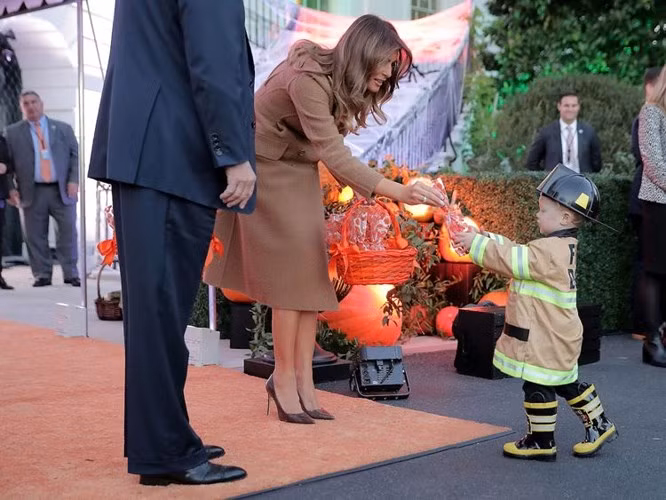 Đệ nhất phu nhân Melania phát kẹo cho một cậu bé "lính cứu hỏa" tí hon tại lễ hội Halloween năm 2017 ở Nhà Trắng.