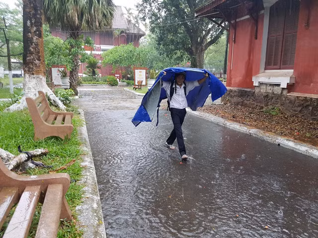 Một thí sinh tự mình đi vào phòng thi sau khi có chiếc áo mưa.