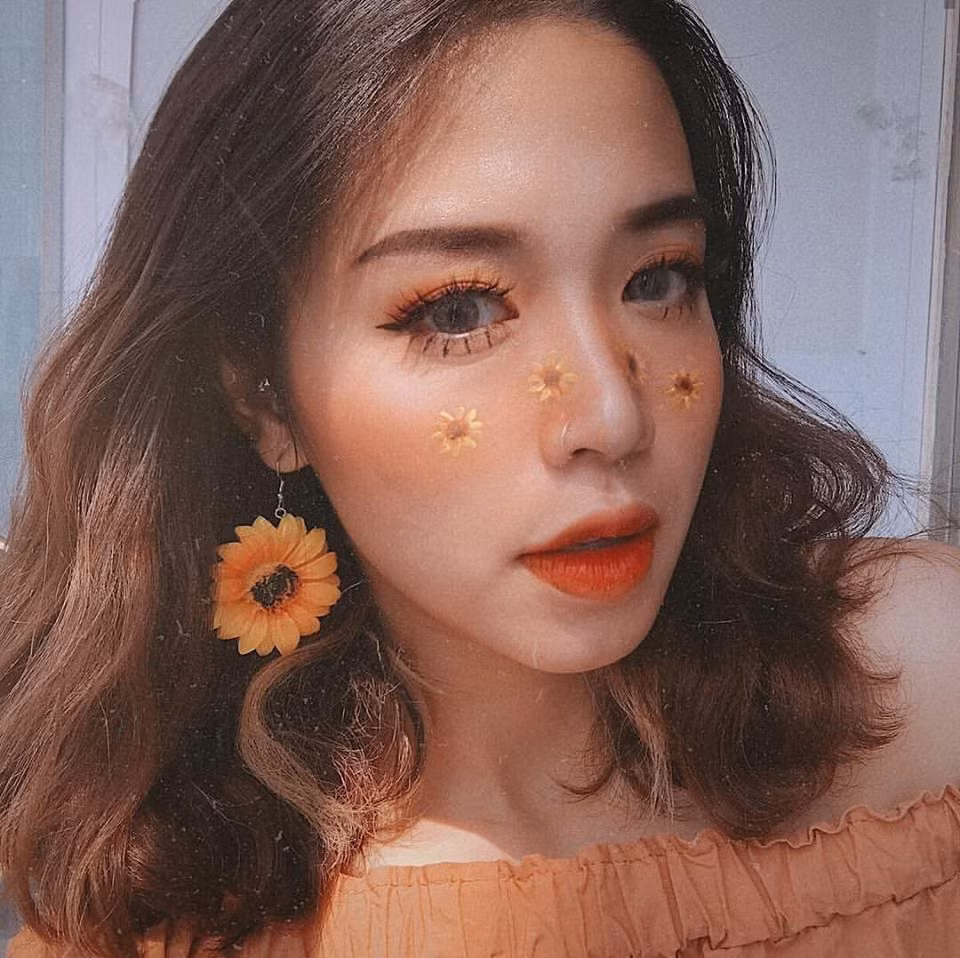 Không còn là kiểu gắn hoa khô quen thuộc, cô nàng này sáng tạo hơn khi vẽ luôn họa tiết hướng dương lên mặt của mình. Phong cách này hoàn toàn phù hợp và độc đáo trong các buổi chụp hình khi bạn muốn có một bộ ảnh đầy ấn tượng. Trông cô nàng xinh đẹp như một bông hoa hướng dương đang khoe sắc.
