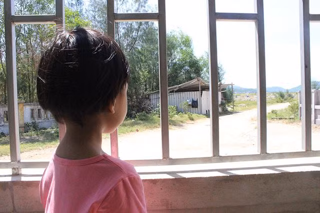 Bé Thùy thường trèo lên thanh cửa trông ra xa xa phía nghĩa trang nơi mẹ em yên nghỉ.