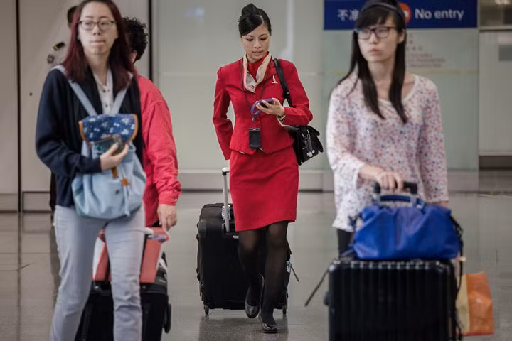 Một nữ tiếp viên hàng không làm việc cho Cathay Pacific (Hong Kong) trong bộ đồng phục màu đỏ.