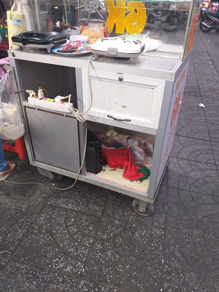 Người mẹ với đứa con thơ năm ngoan ngoãn trong chiếc xe đẩy hàng.