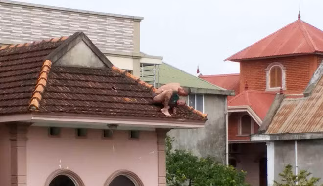 Cháu bé bị người đàn ông khống chế, đưa lên nóc nhà. Ảnh: Nam An.