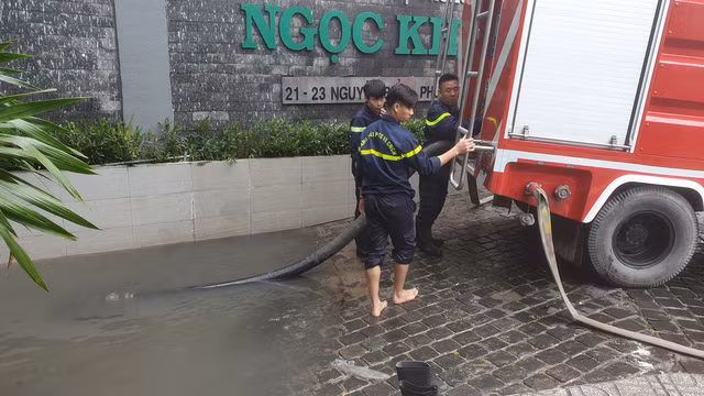Lực lượng cứu hộ triển khai bơm hút nước ra khỏi hầm chung cư bị ngập.