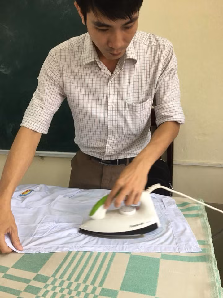 Thầy giáo mang bàn là lên lớp là áo cho học sinh mình tỉ mỉ từng cái một.