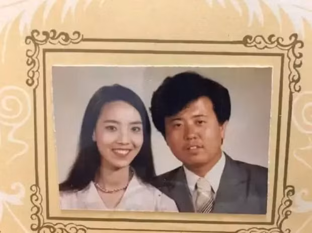 Người vợ xinh đẹp với gương mặt nhỏ nhắn, trắng trẻo và nụ cười tươi tắn đối lập hoàn toàn với người chồng kế bên.