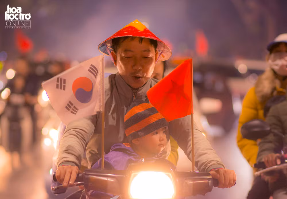 Cổ động viên Việt Nam khi cùng con nhỏ xuống đường ăn mừng chiến thắng nhưng không quên treo cờ của Việt Nam và Hàn Quốc ở 2 bên tay xe