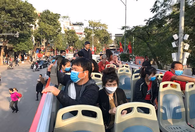 Du khách đến TP Hà Nội được phát khẩu trang miễn phí khi đi xe buýt hai tầng.