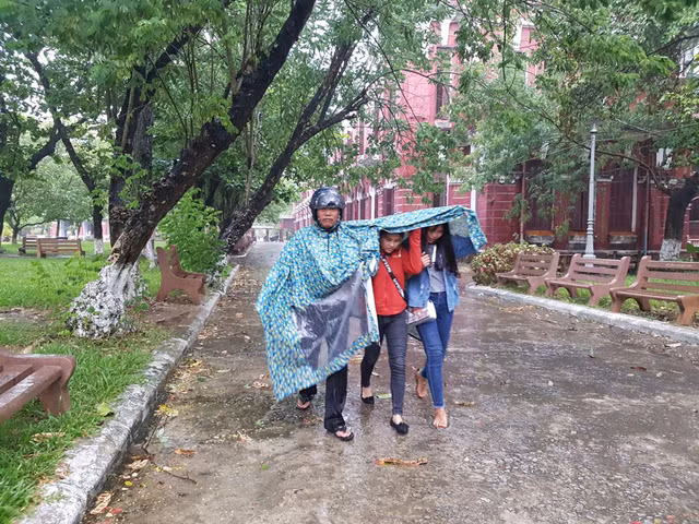 Bố đưa con đi dự thi trong mưa.