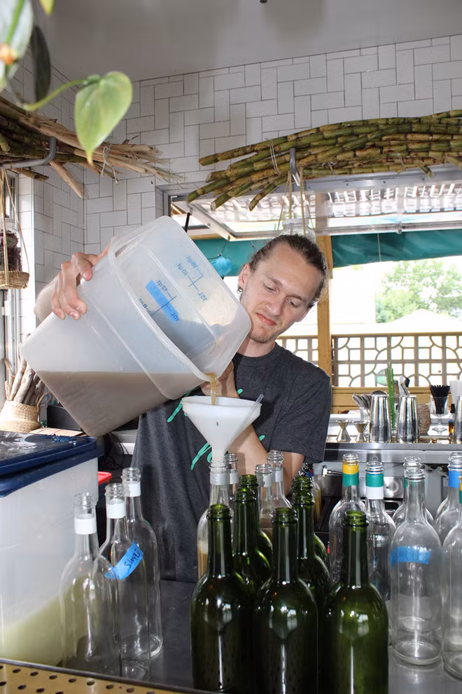Bartender đổ nước mía mới ép để làm cocktail.