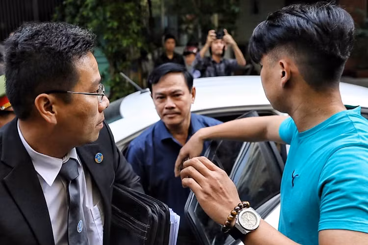 Nguyễn Hữu Linh được che chắn khi vào tòa. Ảnh: Hữu Khoa.
