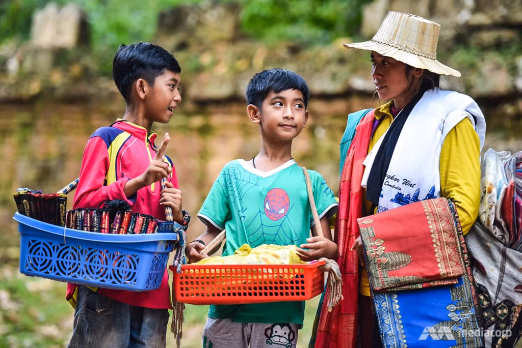 Salik (trái) cùng mẹ và em trai hàng ngày bán rong đồ lưu niệm cho khách du lịch quanh đền Ta Prohm.