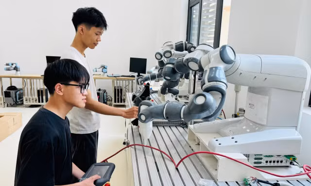 Sinh viên thực hành với cánh tay robot trong phòng Lab Trường ĐH Công nghệ, ĐH Quốc gia Hà Nội. Ảnh: NGHIÊM HUÊ