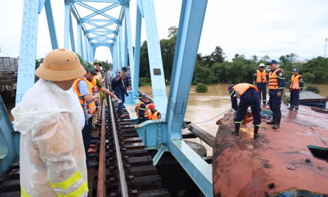 Lực lượng chức năng xử lý, trục vớt các sà lan bị mắc kẹt dưới cầu đường sắt.